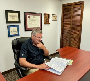 Rod Buckingham sitting at his desk in his Regina office