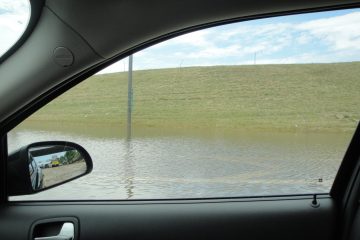 A view from a car window, showing accumulation of water on the streets.